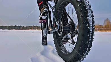 Fat Biker Pedaling Through Deep Snow on Frozen Lake