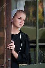Amish Woman Looks out Screen Door