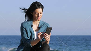 Woman browsing phone content on the beach
