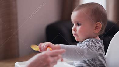 Mother feeding baby girl in highchair