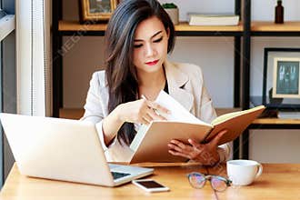Young Asian business woman working at workplace. beautiful Asian woman in casual suit working with reading book,