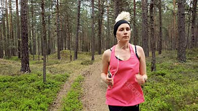 Woman running at forest trail and listening music from smart phone
