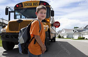 Young boy crossing in front of yellow school bus