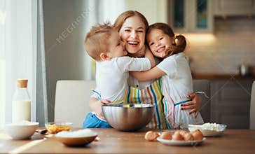 Happy family in kitchen. mother and children preparing dough, bake cookies