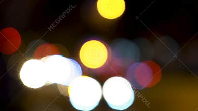 Soft focus bokeh lights of cars, scooters, motorbikes and traffic driving on city streets at night