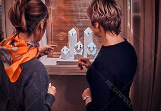 Customer and shop assistant are standing next to display with juwellery and choosing the right ornamentation