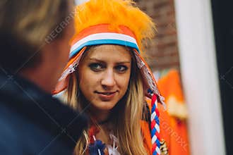 Portrait of woman dressed in orange, crazy hat, King`s Day festivity in the Netherlands