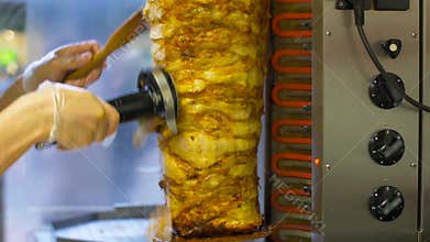 Chef slicing doner meat from spit at kebab shop