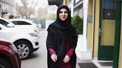 Young attractive woman wearing hijab walking in the street in city and smiling. Slowmotion shot