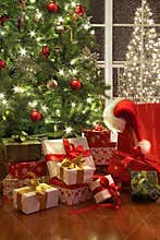 Brightly lit christmas tree with lots of gifts