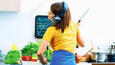 Beautiful woman cooking in kitchen and listen music.