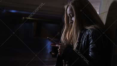 Frightened woman dialing for help at dark tunnel