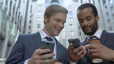 Happy businessmen using easy mobile app on smartphone, colleagues on lunch break