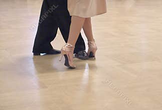 Graceful dance couple tangoing at the ballroom.
