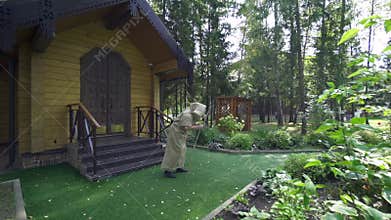 Elderly person wearing hood cloak and walking stick goes bent over from fairytale house