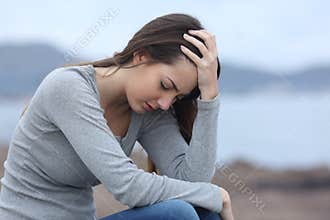 Sad woman on the beach complaining alone