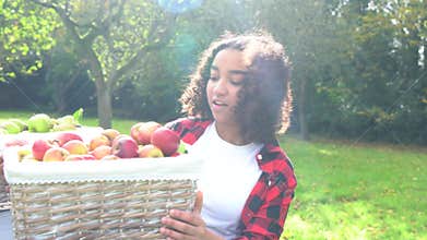 Biracial African American mixed race teenage girl young woman carrying basket of apples