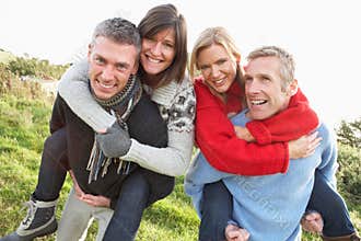 Two Couples Having Piggyback Ride In Autumn