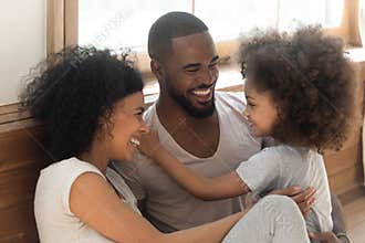 Happy black family bonding laughing sit on bedroom floor