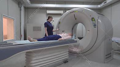 A scanning room with computers and monitors next to the CT scan room in a new modern cancer treatment hospital.