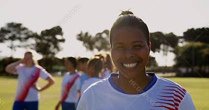 Female soccer player standing while teammates talk on soccer field. 4k