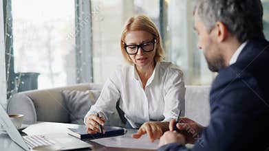 Senior woman entrepreneur negotiating contract with business partner in cafe