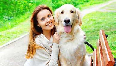 Portrait happy owner woman hugging Golden Retriever dog in city park