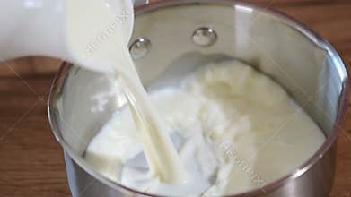 Saucepan pouring hot milk to splash in bowl to breakfast.