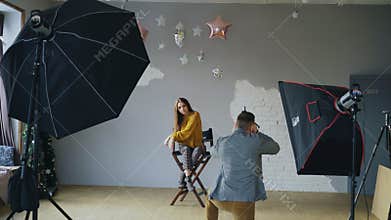 Professional photographer man taking photo of beautiful model girl with digital camera in studio