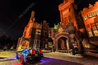 Amazing view of Casa loma old, vintage castle at inviting night time, lit with various lights and car model back to the future