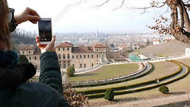 Woman tourist using smart phone, taking picture to urban panorama at Turin, Torino travel destination in Italy.