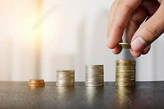 Saving money concept - Male hand putting money coin stack growing business