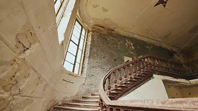 A staircase with wooden railing in an abandoned architectural building. The legacy of past architectural times. Handrail