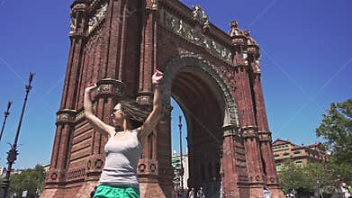 Slow motion of cheerful and beautiful girl spinning around against Arc de Triomf