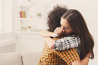 Woman hugging her depressed friend at home