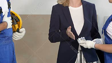 Businesswoman giving a money to builder team for the work standing at the construction site