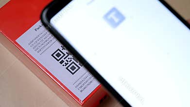 Smartphone scanning QR code in paper label on the orange package or parcel box