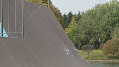 Male skater make turns in ramp in wooden skatepark, long angle in slowmotion