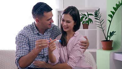 Healthy family couple with pregnancy test happy with positive result and happily hugging each other in room at home