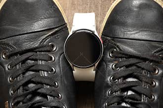 black sneakers and smart watches on the floor, fashion and new technologies, women&#x27;s fitness watch