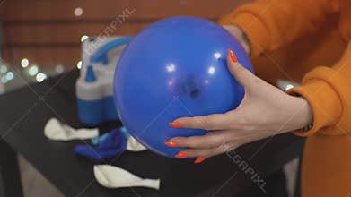 girl blows a blue balloon
