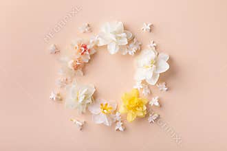 Beautiful floral frame with white narcissus flowers for wedding or greeting card on pastel peach background. Top view and flat lay