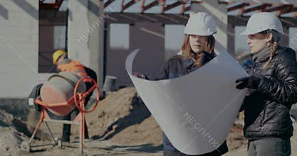 Young female contractor and architect discussing over blueprint