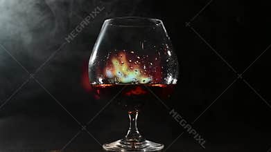 A glass of brandy and cigar smoke in the dark on the background of the fireplace. Gentlemen's club concept