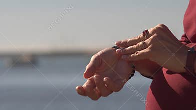 Pregnant woman playing with her ring and bracelet by the sea
