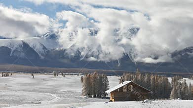 Lonely house and big snow capped mountains in timelapse