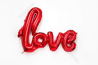 Red golden word LOVE made of inflatable balloons isolated on white background. Red foil balloon letters, concept of