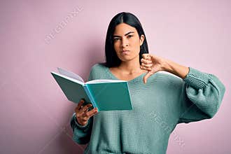 Young beautiful hispanic student woman reading a book over pink isolated background with angry face, negative sign showing dislike