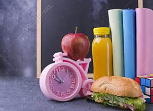 School lunch, books, juice, pink alarm clock, school board for the text with chalk. School break. Free space for text