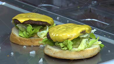 Chef making burger with meat cutlet, cheese, tomato, onion in fast food restaurant kitchen. Cooking delicious hamburgers for